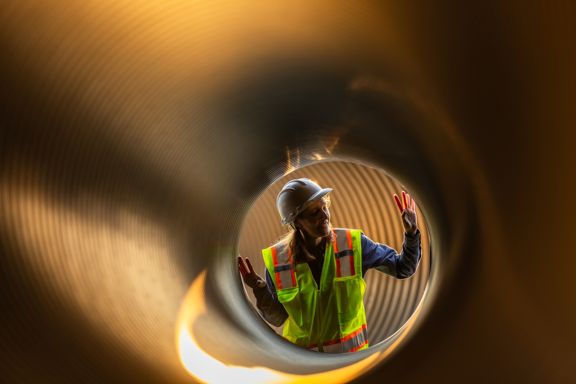 A female engineer inspecting a large pipe from the inside